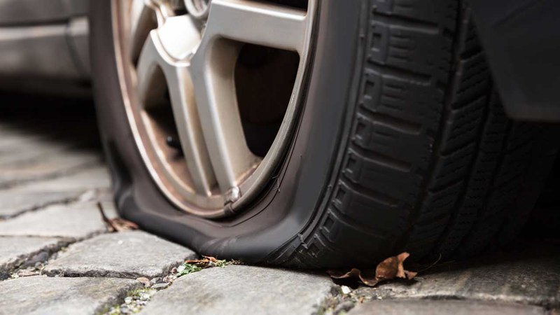 A complete burst tire on the road. The dangers of driving on a flat tire include damaged rims. 