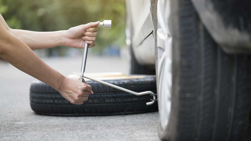 A person changing a tire on the road. Learn what to do with a flat tire while driving on the road. 
