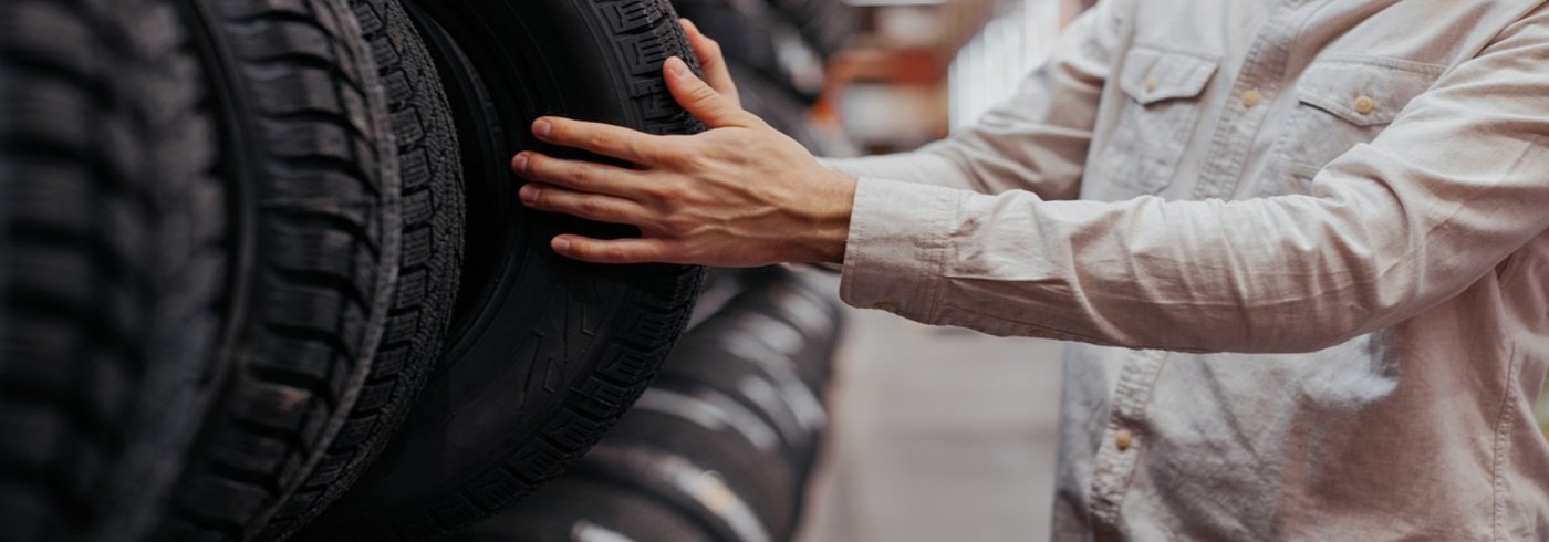 A man in a white shirt is picking tires from a shelf lined with many; this is how to select tires